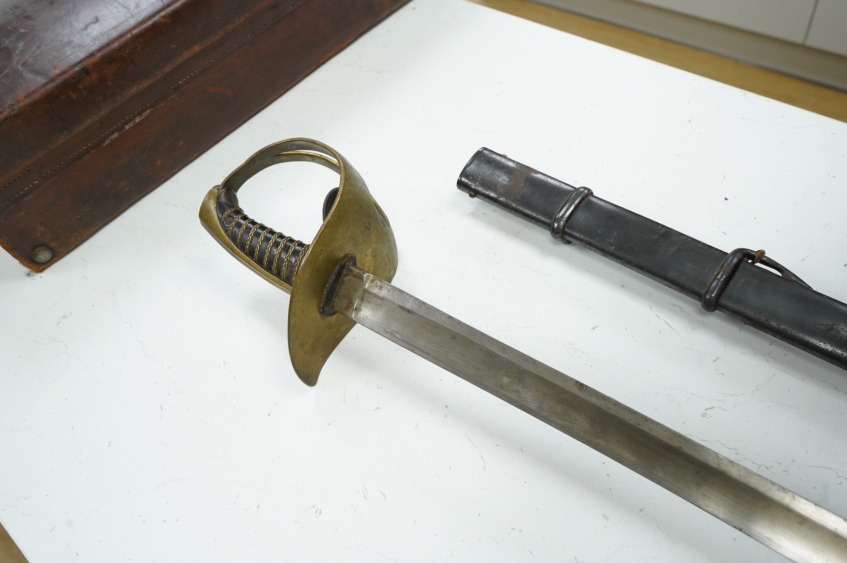 A 19th century Swedish cavalry trooper’s sword, regulation brass guard with pierced opening brass wire bound grip blade struck with military markings, in its black iron scabbard